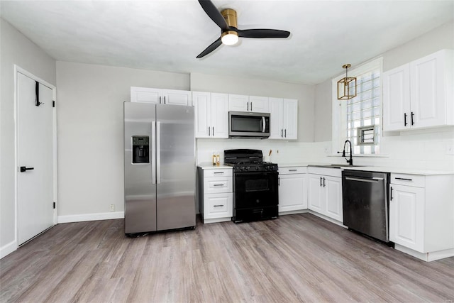 kitchen with a sink, backsplash, appliances with stainless steel finishes, light wood finished floors, and ceiling fan