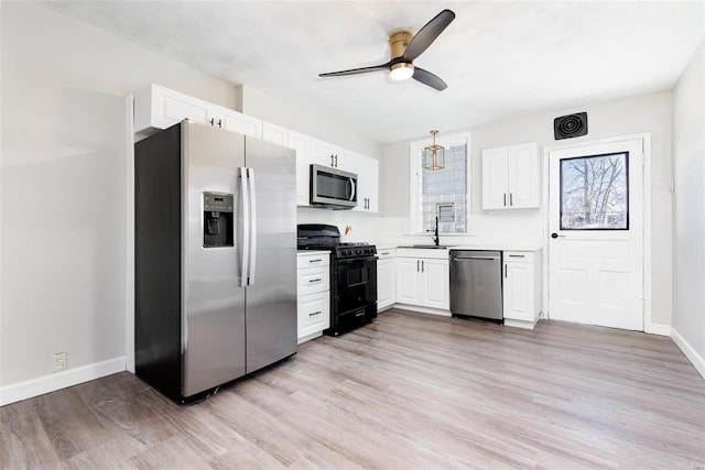 kitchen with appliances with stainless steel finishes, light wood-style floors, a ceiling fan, and a sink