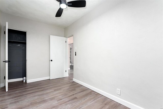 unfurnished bedroom with a ceiling fan, wood finished floors, baseboards, and a closet