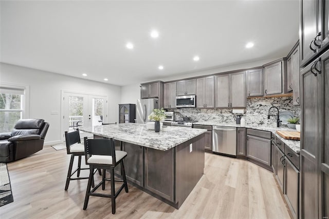 kitchen featuring a breakfast bar, a kitchen island, appliances with stainless steel finishes, a sink, and french doors