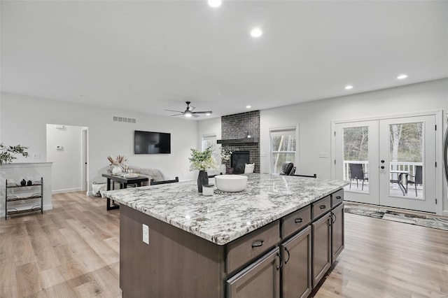 kitchen featuring visible vents, light wood-style flooring, ceiling fan, and a fireplace
