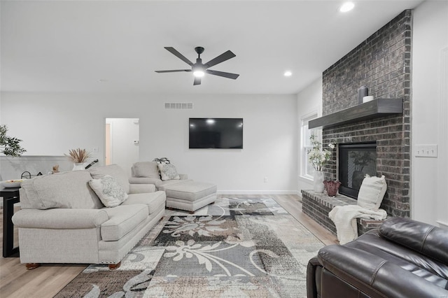 living room with visible vents, a brick fireplace, wood finished floors, recessed lighting, and a ceiling fan