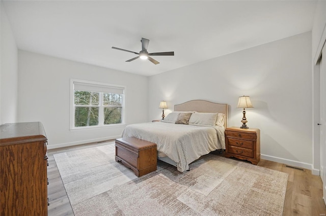 bedroom featuring light wood finished floors, baseboards, visible vents, and ceiling fan