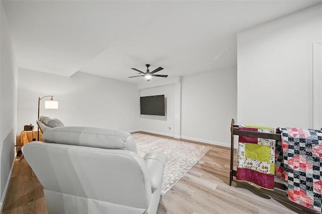 living area featuring light wood-style flooring, baseboards, and ceiling fan