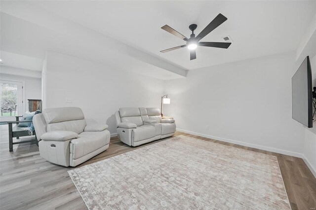 living area with baseboards, light wood-style flooring, and a ceiling fan