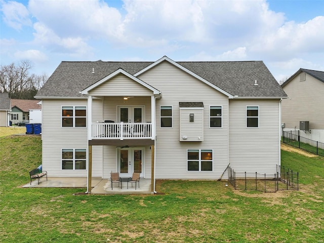 rear view of house featuring a patio, fence, a lawn, and french doors