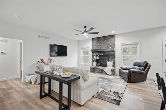living room with a wealth of natural light, light wood-style floors, ceiling fan, and visible vents
