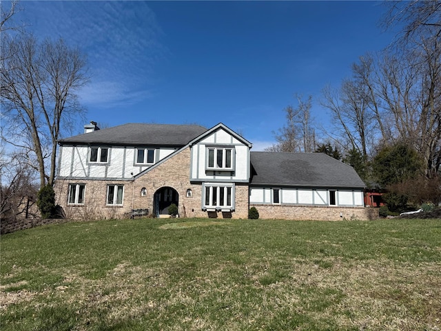 tudor house with a front yard, brick siding, and a chimney