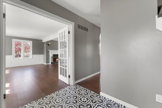 hallway with visible vents, baseboards, wainscoting, and wood finished floors