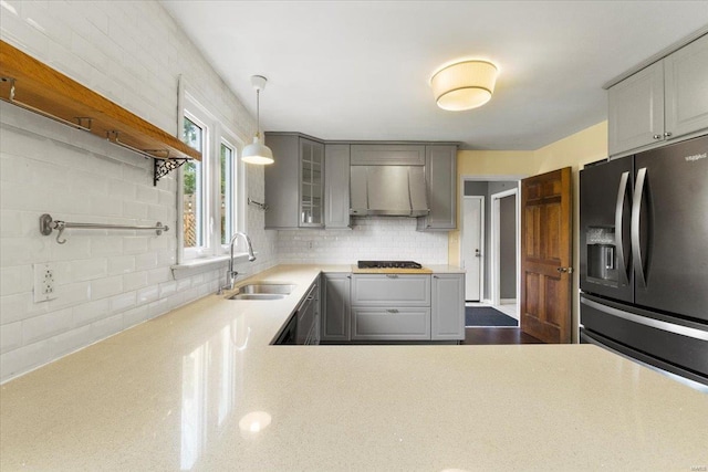 kitchen featuring gray cabinets, light countertops, black refrigerator with ice dispenser, extractor fan, and a sink