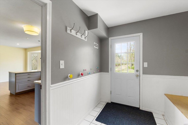 entryway with wood finished floors and a wainscoted wall