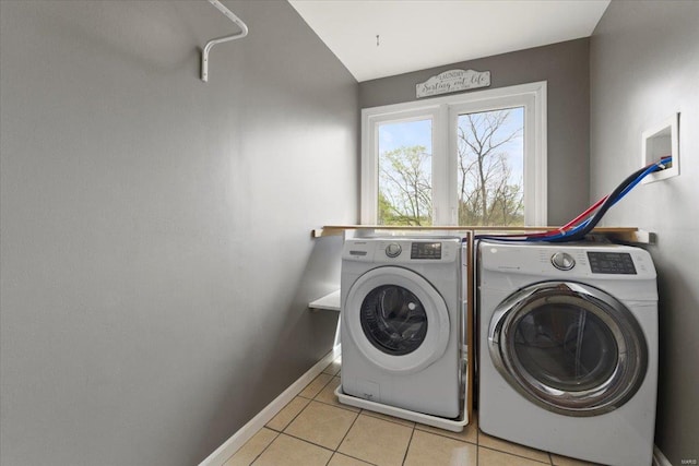clothes washing area with light tile patterned floors, baseboards, washing machine and dryer, and laundry area