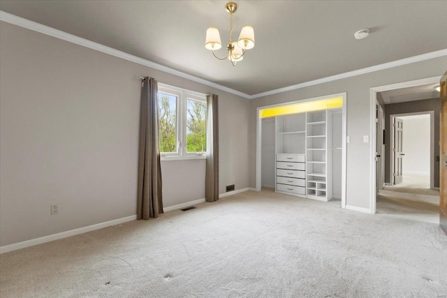 carpeted spare room featuring an inviting chandelier, baseboards, ornamental molding, and visible vents