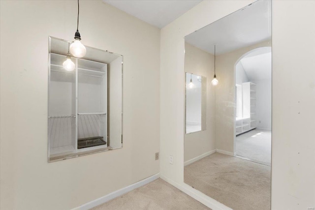 carpeted spare room featuring baseboards and arched walkways