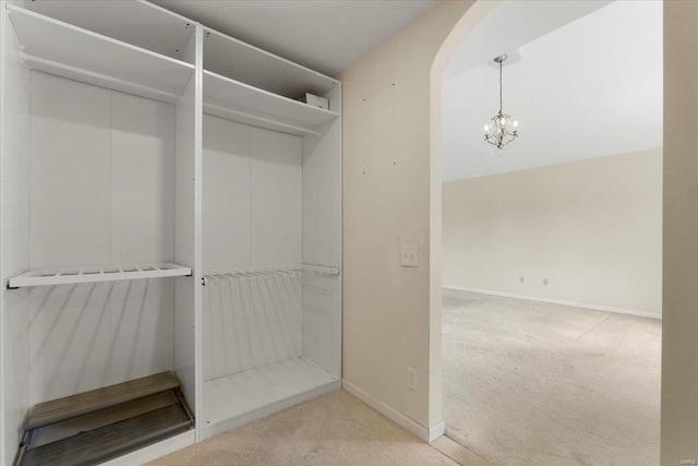 walk in closet with a chandelier, arched walkways, and carpet floors