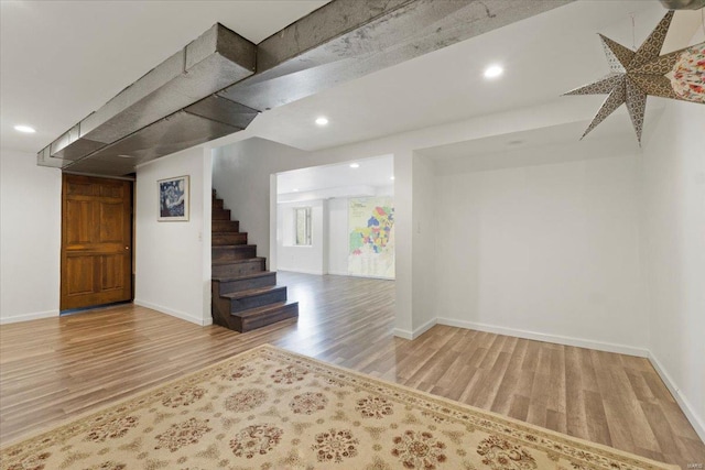 below grade area with wood finished floors, recessed lighting, baseboards, and stairway