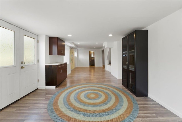 kitchen featuring baseboards, light wood-type flooring, recessed lighting, light countertops, and dark brown cabinets