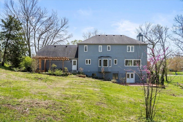 back of house featuring a chimney, a pergola, a patio area, and a yard