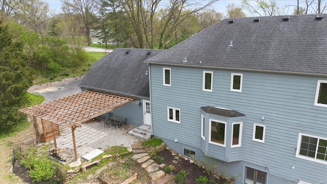 rear view of house featuring a pergola, a patio area, and roof with shingles