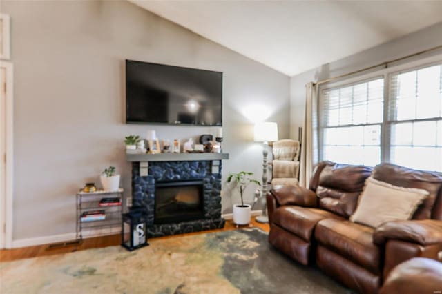 living room featuring lofted ceiling, plenty of natural light, baseboards, and a fireplace