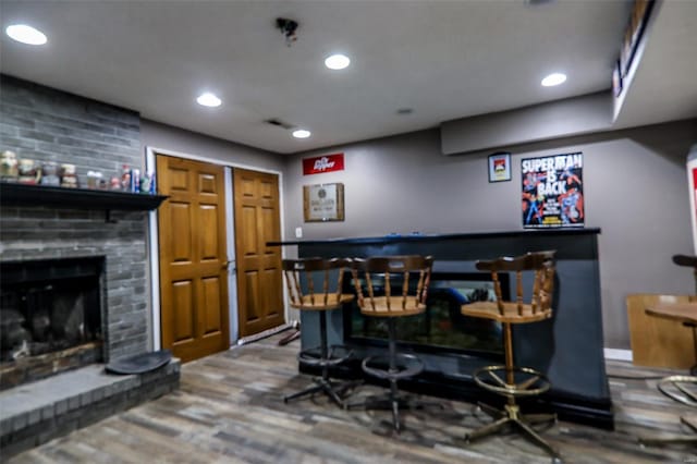 bar with recessed lighting, wood finished floors, a fireplace, and a bar