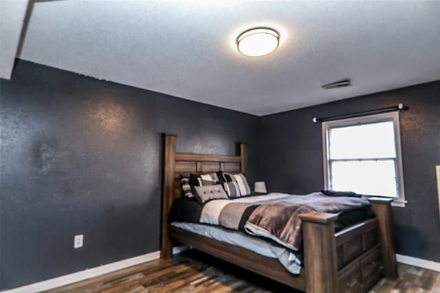 bedroom with wood finished floors, visible vents, and baseboards