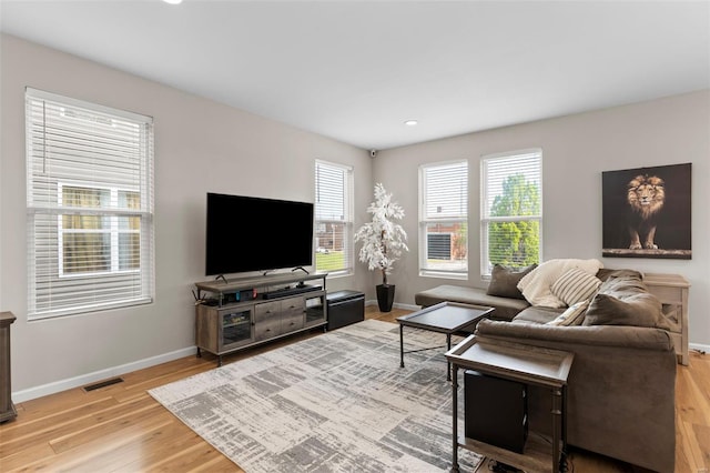 living area with visible vents, light wood-style flooring, and baseboards