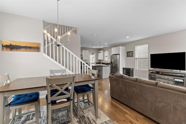 living area with recessed lighting, wood finished floors, a notable chandelier, and stairs