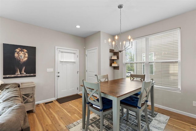 dining area featuring baseboards, an inviting chandelier, light wood-style flooring, and plenty of natural light