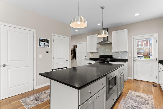 kitchen with dark countertops, electric range oven, light wood-style flooring, and wall chimney exhaust hood