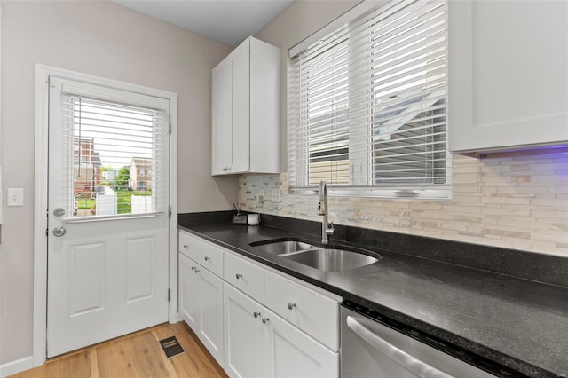 kitchen featuring a wealth of natural light, dark countertops, dishwasher, and a sink