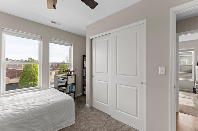 carpeted bedroom with a closet, visible vents, a ceiling fan, and baseboards