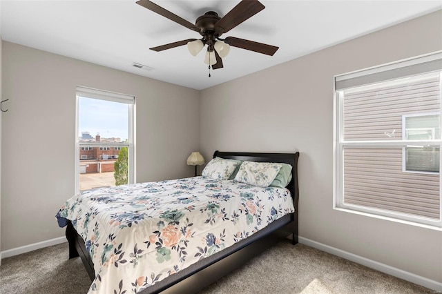 carpeted bedroom with visible vents, a ceiling fan, and baseboards
