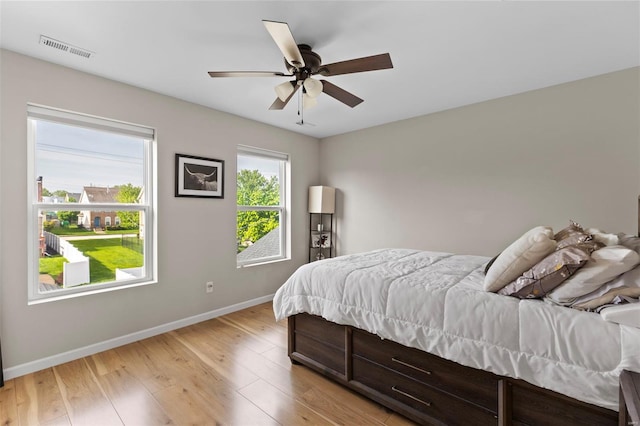 bedroom featuring baseboards, visible vents, ceiling fan, and light wood-style flooring