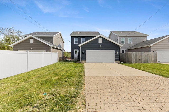 exterior space with concrete driveway, a lawn, an attached garage, and fence