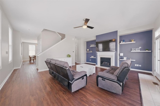 living room featuring baseboards, stairs, wood finished floors, and a ceiling fan