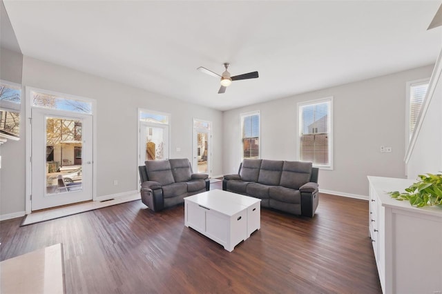 living area featuring plenty of natural light, dark wood-style floors, and a ceiling fan