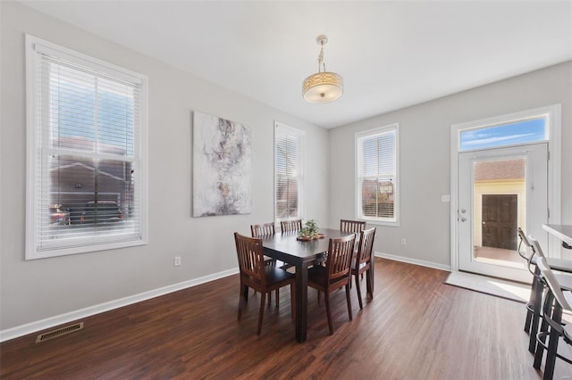 dining area with baseboards, visible vents, and wood finished floors