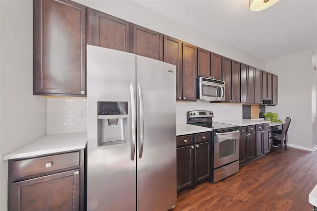 kitchen with tasteful backsplash, dark brown cabinetry, appliances with stainless steel finishes, and dark wood-style flooring