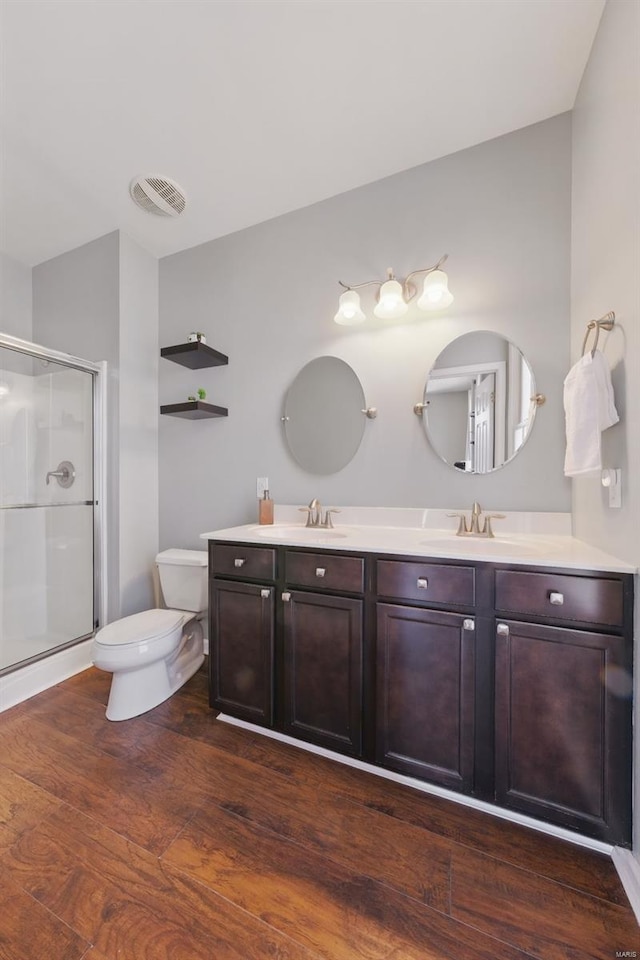 full bath featuring toilet, a sink, a stall shower, visible vents, and wood finished floors