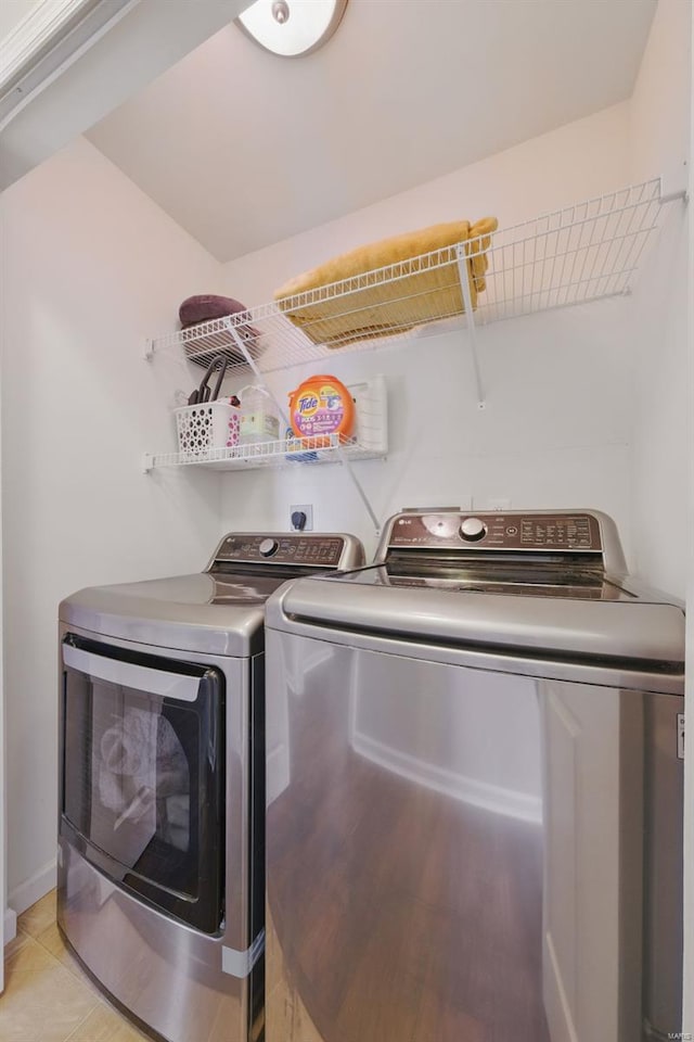 clothes washing area featuring light tile patterned floors, washer and clothes dryer, and laundry area