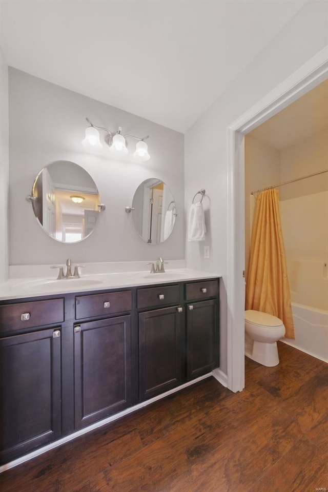 bathroom with toilet, a sink, shower / bathtub combination with curtain, wood finished floors, and double vanity