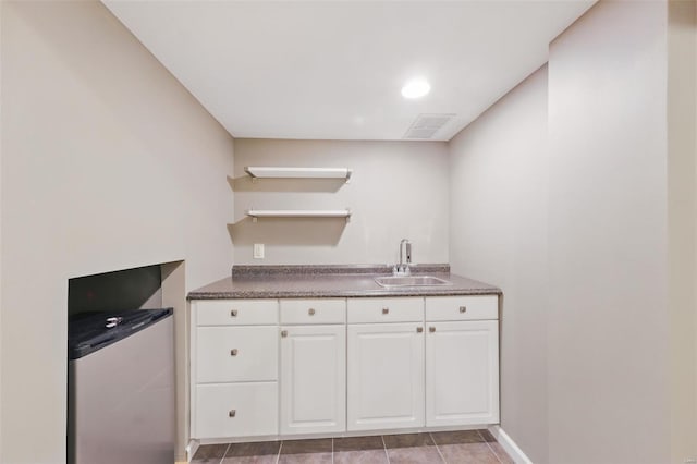 kitchen featuring visible vents, white cabinetry, a sink, open shelves, and fridge