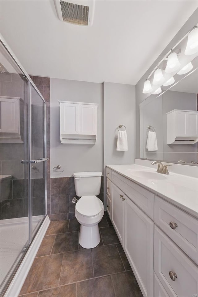 bathroom featuring a shower stall, visible vents, toilet, and vanity