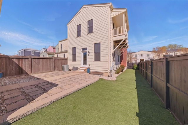 back of house with a balcony, entry steps, central AC, a fenced backyard, and a lawn