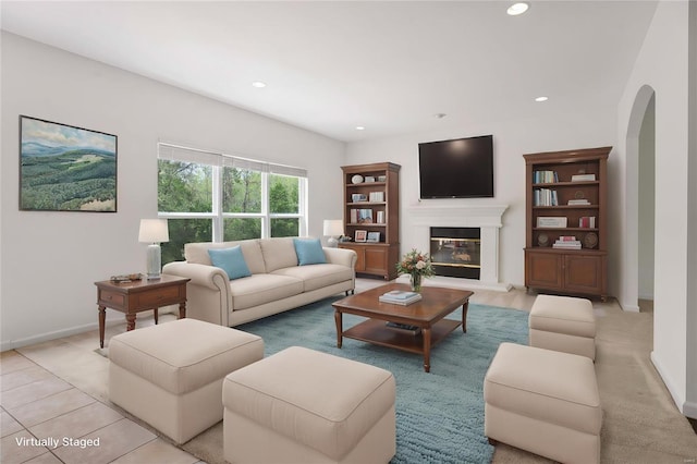 living room featuring baseboards, recessed lighting, arched walkways, and a glass covered fireplace