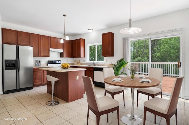 kitchen featuring hanging light fixtures, range, under cabinet range hood, light countertops, and stainless steel refrigerator with ice dispenser