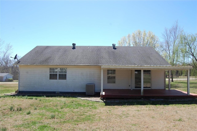 rear view of property featuring a shingled roof, central air condition unit, and a lawn