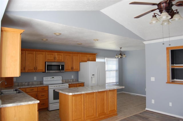 kitchen featuring vaulted ceiling, white appliances, ceiling fan with notable chandelier, a kitchen island, and a sink