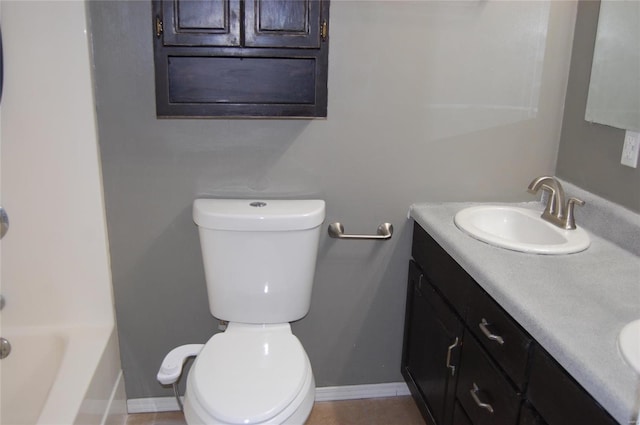 full bath with double vanity, toilet, baseboards, and a sink